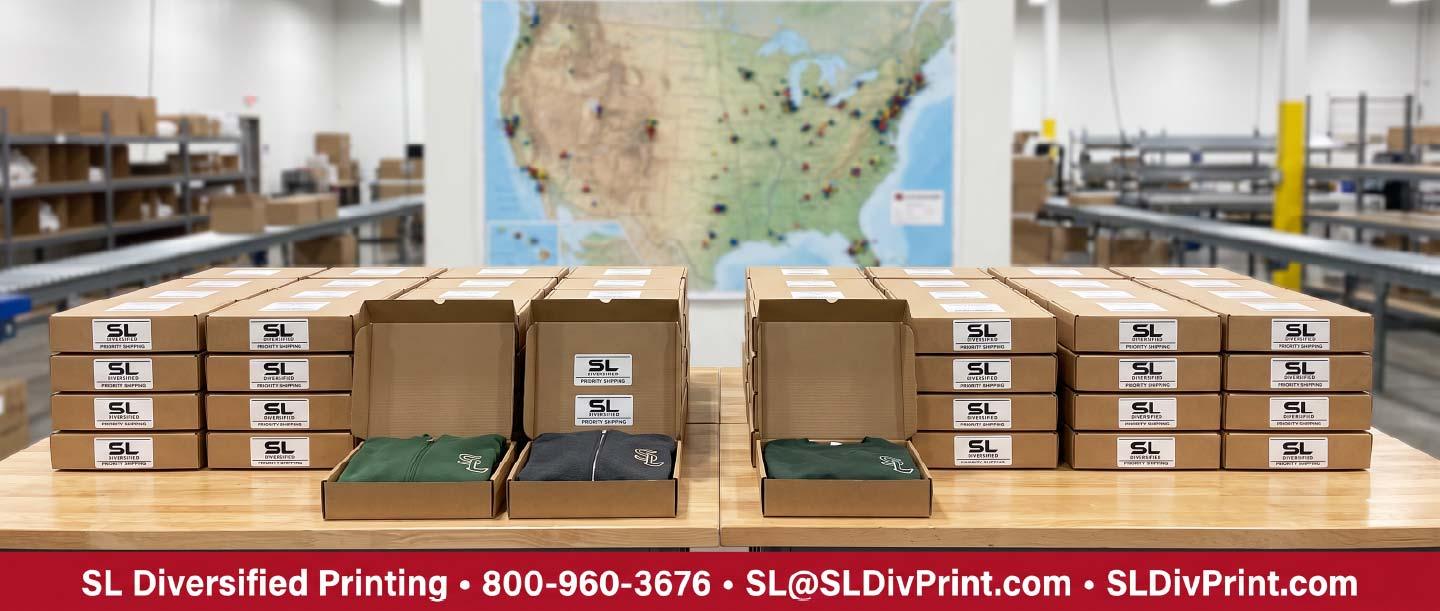 Neatly stacked folded branded apparel and labeled cartons on warehouse shelving with a hand scanning a carton label